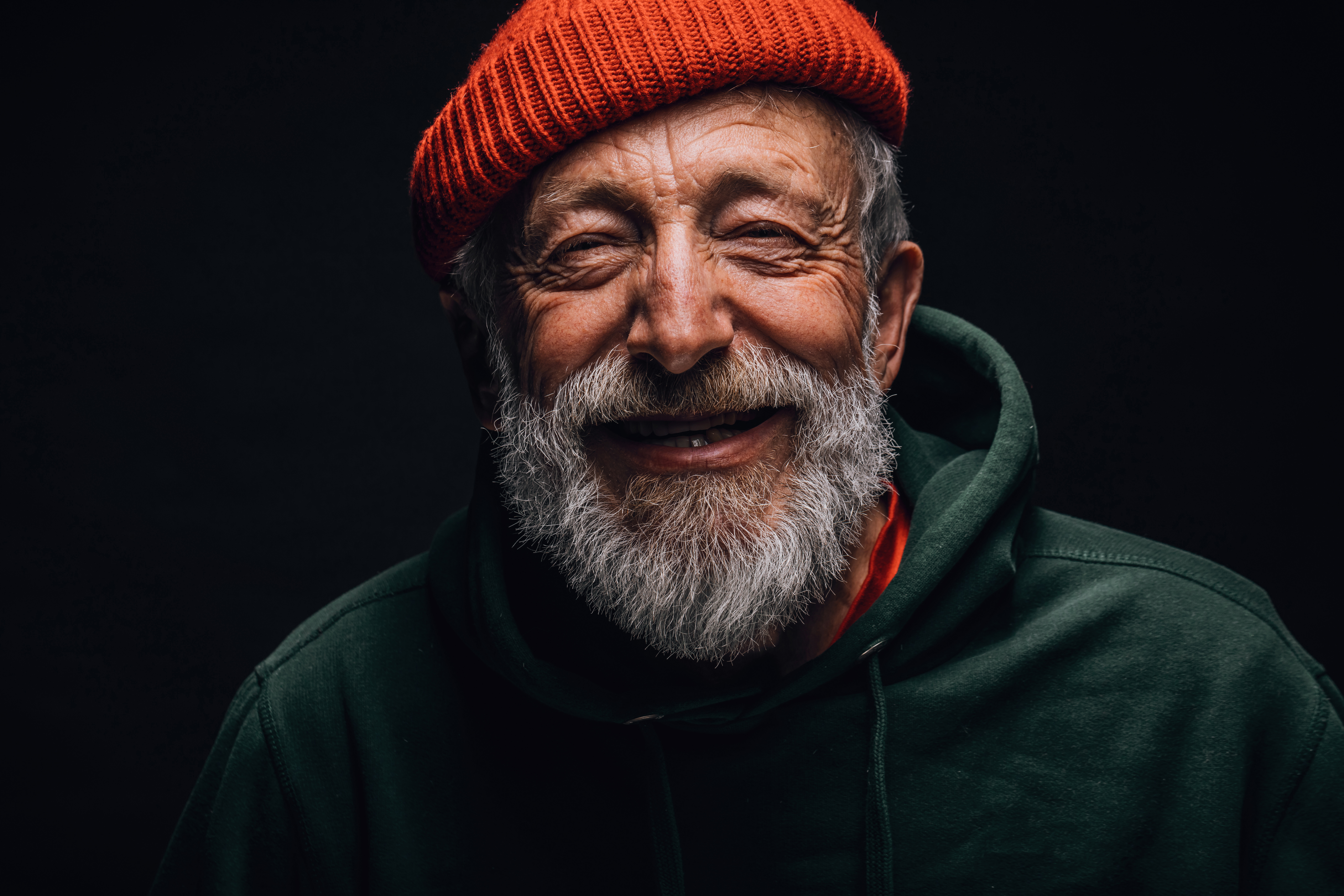 Old man wearing a red beannie and smiling