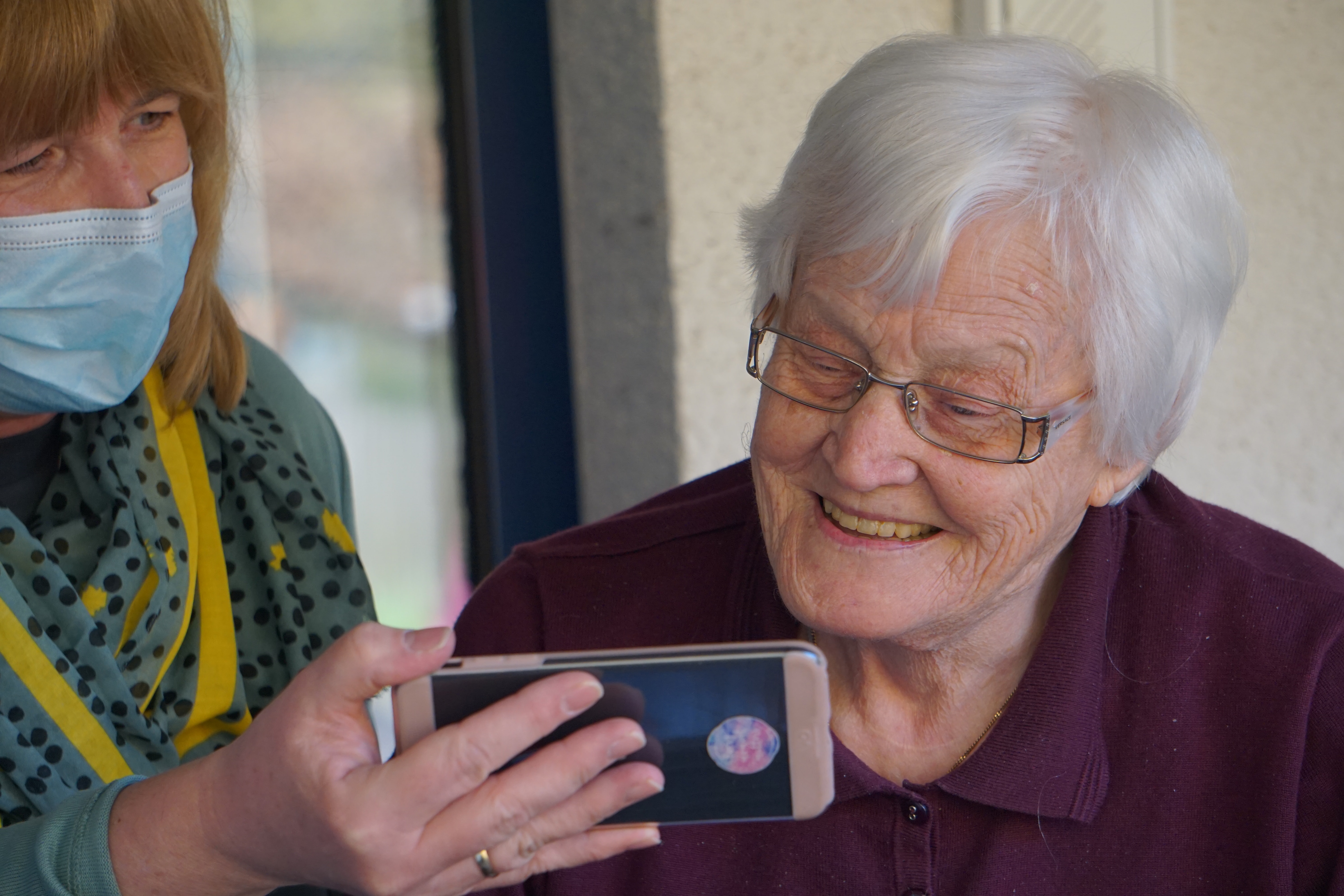 One lady showing something on her cell to another old lady